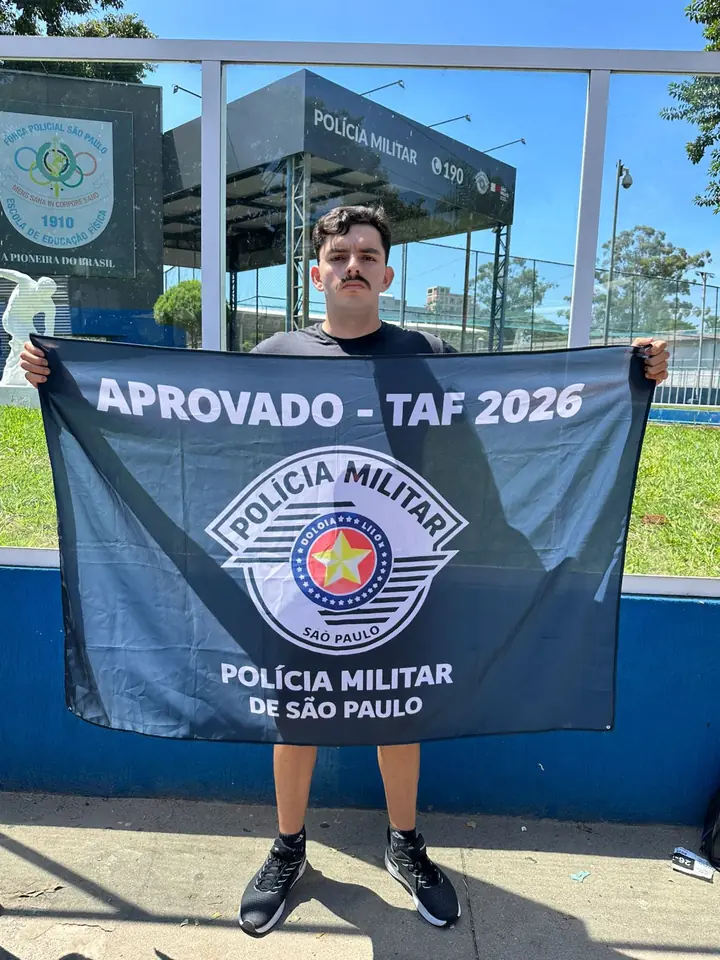 Aluno aprovado segurando bandeira de aprovação no TAF